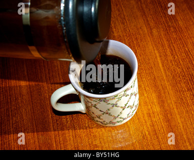 Kaffee aus der Kaffeemaschine Glas französischen Presse in Porzellan-Becher gießen Stockfoto