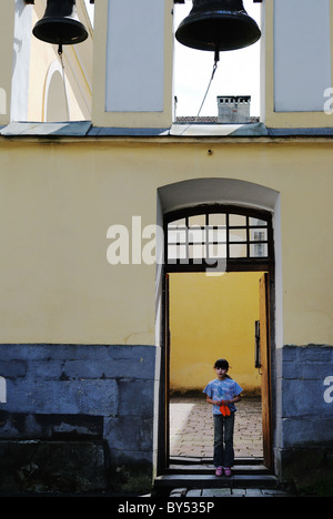 Mädchen mit Papier Flugzeug stehen am Eingang der Kirchhof, Lemberg, Ukraine Stockfoto