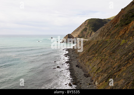 Wellen gegen die Felsenküste in Big Sur mit Big Creek Bridge entlang der kalifornischen Pacific Coast Highway, Kalifornien, USA. Stockfoto