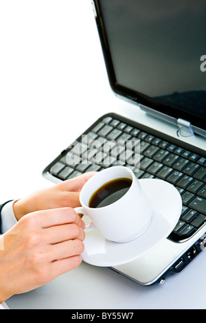Nahaufnahme der Geschäftsfrau die Hände mit einer Tasse Kaffee über offene laptop Stockfoto