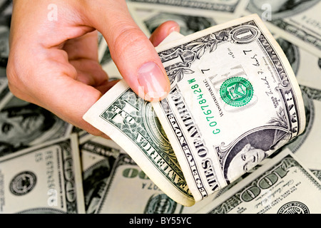 Nahaufnahme von Frauenhand mit ein-Dollar-Banknote auf dem Hintergrund von vielen US-Dollar Stockfoto