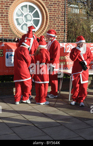 Leute, gekleidet in Santa-Outfits warten zu Beginn der Jingle Bell Jog Volkslauf Stockfoto