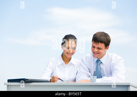Porträt von Mann und Frau am Schreibtisch sitzen und miteinander interagieren Stockfoto