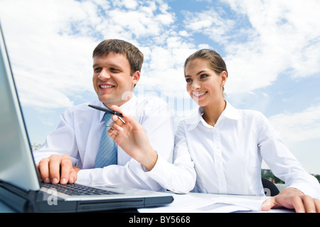 Porträt von interagierenden Geschäftsleute: Frau zeigt auf Laptop-Monitor und Mann, der ihr zuhört Stockfoto