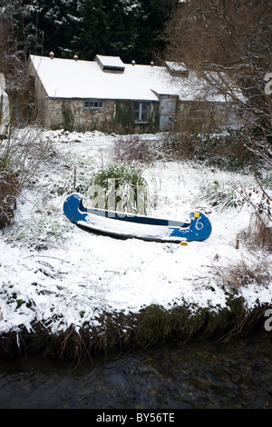 Eine Kajak sitzt auf den Schnee bedeckten Ufer des Flusses in Gweek, Cornwall. Stockfoto