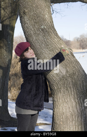 Junge Frau umarmt einen Baum im Prospect Park in Brooklyn, New York Stockfoto