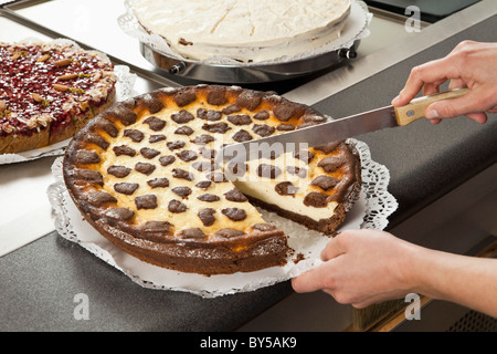 Eine Verkäuferin, schneiden ein Stück Schokoladen-Käsekuchen Stockfoto