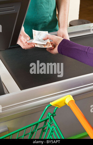 Ein Kunde Übergabe einer Kasse Bargeld im Supermarkt Stockfoto