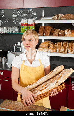 Eine Verkäuferin hält einen Korb mit Baguette Stockfoto