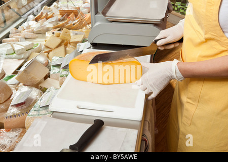 Eine Verkäuferin Käse an der Käsetheke schneiden Stockfoto