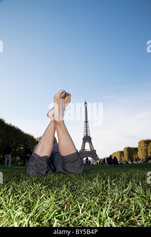 Eine Frau, die Verlegung in Grass von Eiffelturm, Fokus auf Füßen Stockfoto