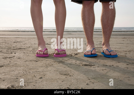 Ein junges Paar Flip Flops am Strand, niedrige Abschnitt tragen Stockfoto