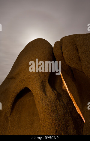 Mond scheint hinter großen Granitfelsen in der Nacht im Joshua Tree National Park, Mojave-Wüste, Kalifornien, USA. Stockfoto