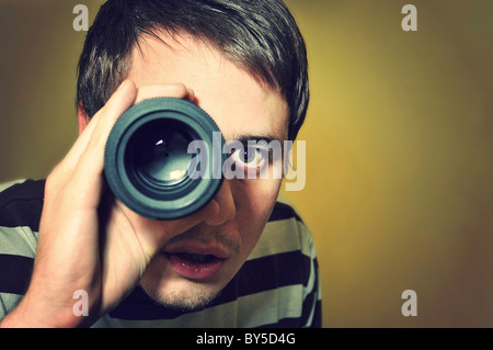 Hübscher junger Mann hält Kameraobjektiv wie es wurde spyglass Stockfoto