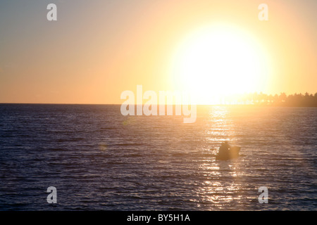 In der Reflexion eines Sonnenuntergangs ist ein kleines Boot gefangen. Stockfoto