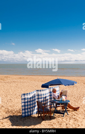 Ein Mann, entspannen, lesen eine Zeitung am Strand in Southwold, Suffolk, England, Großbritannien, Uk Stockfoto