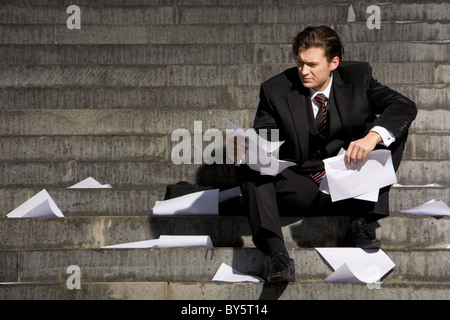 Unglückliche Geschäftsmann weltweite Finanzkrise leiden, beim Sitzen auf der Treppe Stockfoto