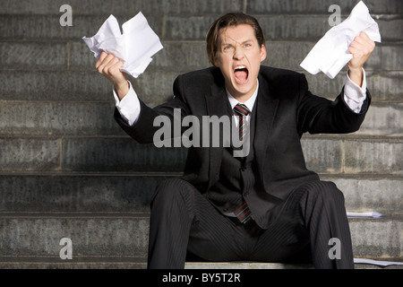 Foto von schreienden Geschäftsmann mit zwei Blatt Papier in seinen Händen Stockfoto