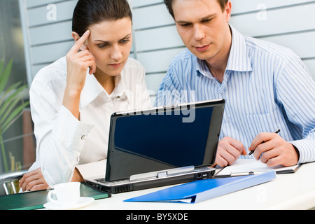 Junge Geschäftsfrau und Geschäftsmann, Blick auf den Monitor des Laptops auf den Tisch gelegt Stockfoto