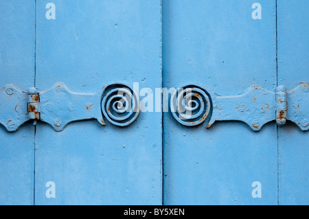 Symmetrische Metallscharniere mit einer dekorativen Spirale auf blau lackierten hölzernen Fensterläden in Frankreich Stockfoto