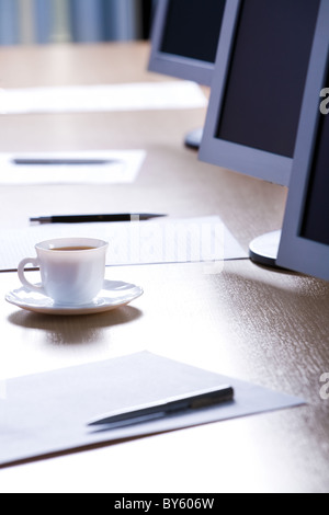 Bild von Tasse, Papiere, Stifte und Monitoren platziert auf einem Tisch Stockfoto