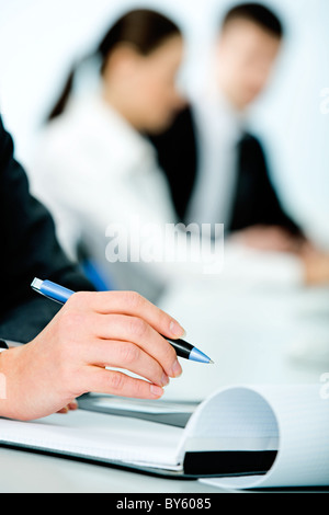Nahaufnahme von Frauenhand hält einen Stift auf dem Hintergrund der Menschen Stockfoto