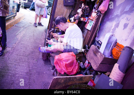Alte chinesische Mann reparieren Schuhe auf der Straße die altmodische Art und Weise in Hong Kong, China Stockfoto