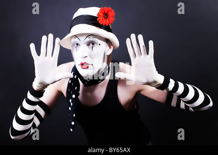 Lustige Mime in weißen Hut mit roter Blume auf einem schwarzen Hintergrund Stockfoto