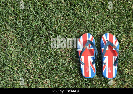 Flip Flops platziert auf dem Rasen mit einem britischen Union Jack-Flagge bedruckt Stockfoto