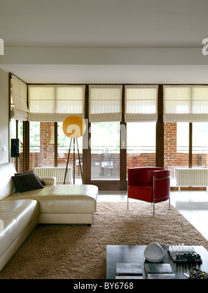 moderne Sofa Beige Leder und Sessel aus rotem Leder in der Nähe ein großes Fenster Stockfoto