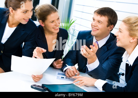 Porträt von vier erfolgreiche Menschen rund um den Tisch versammelt und diskutieren eine neue Geschäftsstrategie im Büro Stockfoto