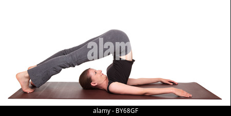 Studioaufnahme einer Fit kaukasischen Frau hält die Halasana Pflug Pose Yogaposition auf eine Gymnastikmatte isoliert. Stockfoto