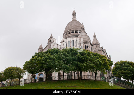 Sacré-Coeur-Basilika Weiße Kuppelfassade Montmartre Paris Frankreich // PARIS, Frankreich — die Basilika Sacré-Cœur, eine prominente Kathedrale mit weißer Kuppel, befindet sich in Montmartre auf dem höchsten Punkt von Paris. Die Basilika wurde aus Travertinstein von Château-Landon erbaut und 1914 fertiggestellt. Es wurde 1919 nach dem Ende des Ersten Weltkriegs offiziell geweiht. Dieses Wahrzeichen ist eine bedeutende religiöse und kulturelle Stätte und bietet einen weiten Blick über die Stadt. Seine unverwechselbare romanisch-byzantinische Architektur zieht Besucher mit seinem atemberaubenden Äußeren und seiner ruhigen Inneneinrichtung an. Stockfoto