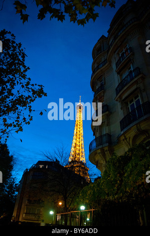 Eiffelturm beleuchtet bei Nacht mit Haussmannian Building Paris France // PARIS, Frankreich – der Eiffelturm ist mit goldenen Lichtern und einer glitzernden Ausstellung bei Nacht beleuchtet. Ein klassisches Haussmann-Gebäude, das sich durch seine kunstvollen Balkone und die Steinfassade auszeichnet, rahmt die ikonische Struktur ein. Dieser von Gustave Eiffel entworfene Eisenturm wurde 1889 als Eingangsbogen zur Weltausstellung 1889 fertiggestellt. Er ist 330 Meter (1.083 Fuß) hoch, einschließlich seiner Antenne. Der Eiffelturm ist ein weltweites Kultursymbol und eines der bekanntesten Wahrzeichen Frankreichs. Stockfoto