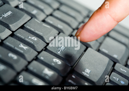 Nahaufnahme des Fingers über schwarzer Laptop Tasten zu drücken enter-Taste Stockfoto