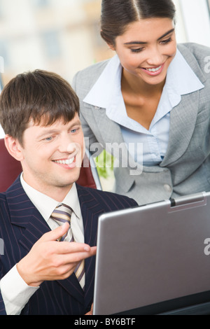 Porträt von lächelnden Mann zeigte am Laptop-Bildschirm mit erfolgreichen Geschäftsfrau in der Nähe von Stockfoto