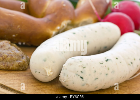 Weißwurst mit Brezel und süßem Senf als Closeup auf ein Schneidebrett Stockfoto