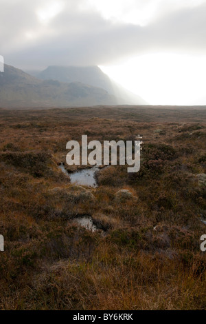 Einen dramatischen Blick auf die Sonne bricht durch die Wolken auf einem herbstlichen Moor in den Highlands von Schottland. Stockfoto