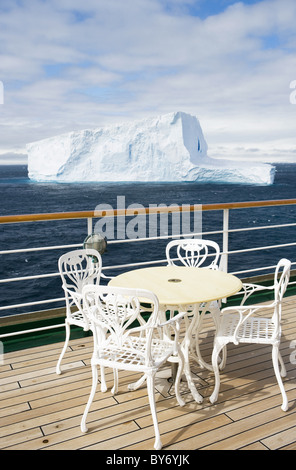 Tisch auf dem Deck des Kreuzfahrtschiff MS Deutschland (Deilmann Kreuzfahrten) und Blick auf antarktischen Eisberges, Süd-Shetland-Inseln, Antarktis Stockfoto