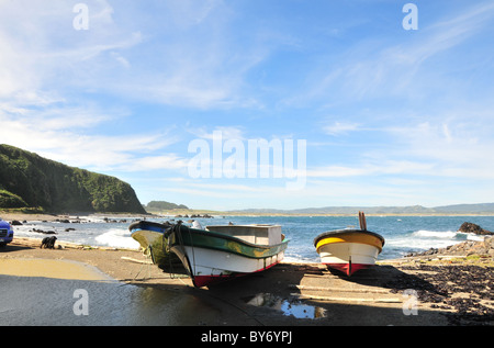 Drei kleine Fischerboote vertäut am Log Helligen Nord Seite Cocotue Bay, Mar Brava Pazifischen Ozean Küste, Insel Chiloe, Chile Stockfoto