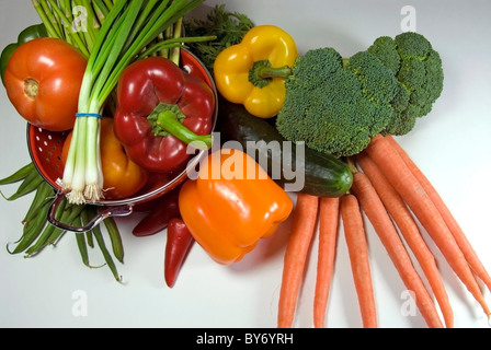 Pflanzliche Anordnung mit Karotten, Broccoli, Zwiebeln, Tomaten, Paprika, Gurken und ein Sieb. Stockfoto