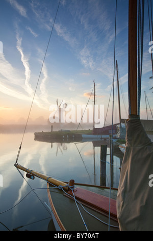 Thurne Windpumpe mit einem traditionellen Holzboot Segeln im Vordergrund auf den Norfolk Broads im Morgengrauen Stockfoto