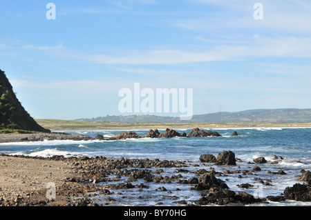 Blauer Himmelsblick landeinwärts Meer Wellen schlagen Basaltfelsen unter Klippen, Mar Brava, Pacific Coast, Cocotue Bay, Insel Chiloe, Chile Stockfoto