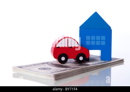 rotes Auto und blaue Haus über eine Menge von Dollarnoten isoliert auf weiss (Tiefenschärfe) Stockfoto