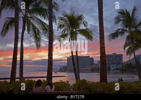 Menschen und Palmen Bäume am Waikiki Beach bei Sonnenuntergang, Honolulu, Oahu, Hawaii, USA, Amerika Stockfoto