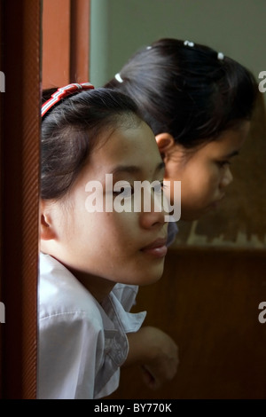 Zwei junge Gehörlose Studentinnen sind auf einem Fensterbrett ihre Klassenzimmer in ein Reha-Zentrum in kommunistische Laos gelehnt. Stockfoto