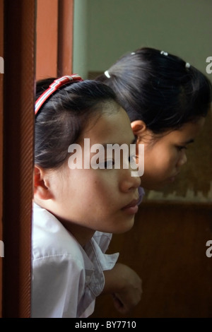 Zwei junge Gehörlose Studentinnen sind auf einem Fensterbrett ihre Klassenzimmer in ein Reha-Zentrum in kommunistische Laos gelehnt. Stockfoto