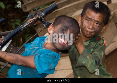 Zwei jungen mit schmutzigen Gesichtern Spaß während des Lebens in Armut als Schrägstrich und brennen Subsistenz Bauernhof Kinder in Vang Vieng, Laos Stockfoto