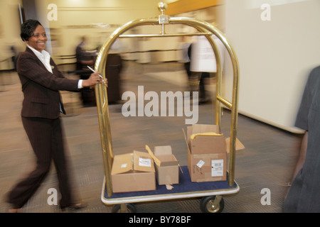 Atlanta Atlanta Georgia, Hyatt Regency, Hotel, Unterkunft, Kette, Gastfreundschaft, Lobby, Messinggepäck, Kofferwagen, Schwarze Frau weibliche Frauen, schieben, Boxen, Hotelpage Stockfoto