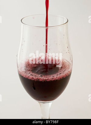 Rotwein in ein Glas gießen, über weiß Stockfoto